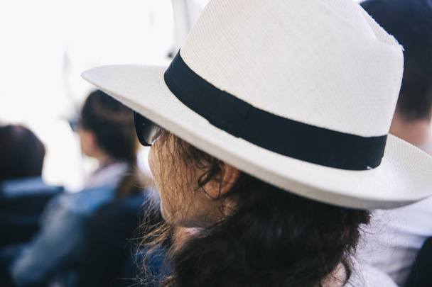 Zadní pohled na mladou ženu s bílým kloboukem na hlavě - Fotografie, Obrázek