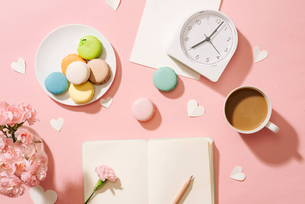 color macaroons, blank notebook and coffee cup on pink table - Fotó, kép