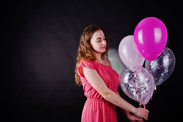Young girl in red dress with balloons against black background o - Foto, Imagen