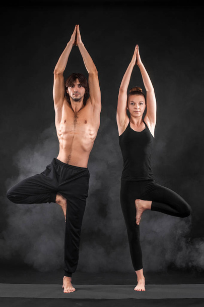 Acroyoga. Young couple practicing acro yoga on mat in studio together. Couple yoga. Partner yoga. Black and white photo. - Foto, Imagen