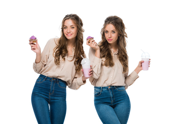 attractive young twins with cupcakes and milkshakes isolated on white - Foto, Bild