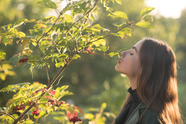spring time! young girl at viburnum or rowan tree sunny outdoor. woman stand near tree in spring. spa therapy and treatment, nature. beauty and youth fashion. - Foto, afbeelding