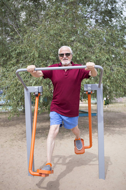 Старший мужчина тренируется на спортивном оборудовании на открытом воздухе
 - Фото, изображение