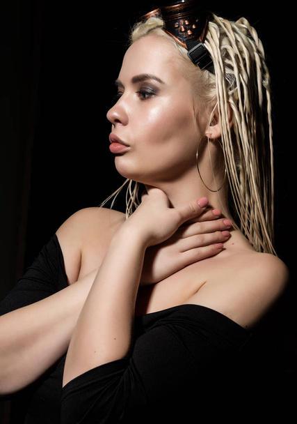 sexy blonde beautiful woman with dreadlocks on a dark background in the studio - Фото, изображение