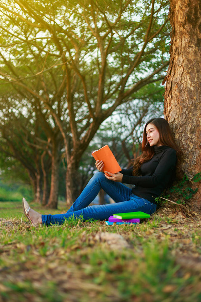 young woman sitting and reading a book in park - Foto, Imagem