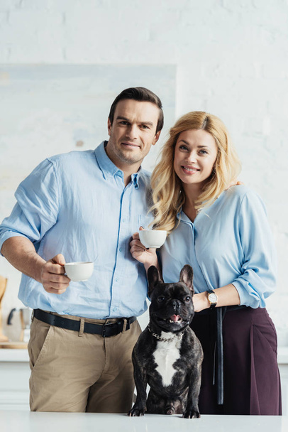 Man and woman drinking coffee by their dog on kitchen table - Foto, immagini