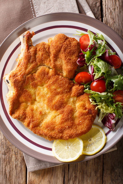 Veal milanese (cotoletta alla milanese) with lemon and fresh veg - Foto, afbeelding