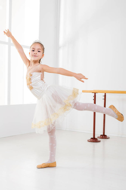 Schattig klein meisje beoefenen van ballet en kijken naar camera. - Foto, afbeelding