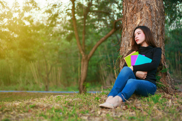 young woman sitting and holding a book in park - Foto, Imagem