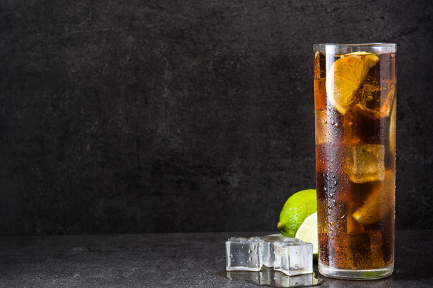 Cuba libre. Cocktail with rum, lime and ice on black stone. Copyspace - Photo, Image