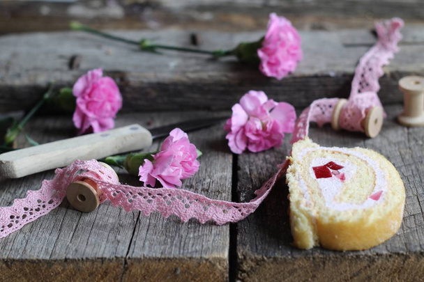 biscuit deeg rollen, houten klossen, mes en roze carnation bloemen op houten, vintage achtergrond - plat lag voedsel achtergrond  - Foto, afbeelding