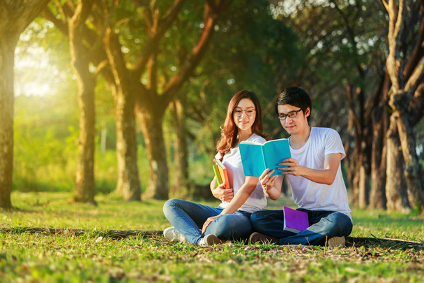 man and woman sitting and reading a book in the park - Foto, Imagen