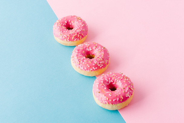 Three pink donuts on multicolored background - Φωτογραφία, εικόνα