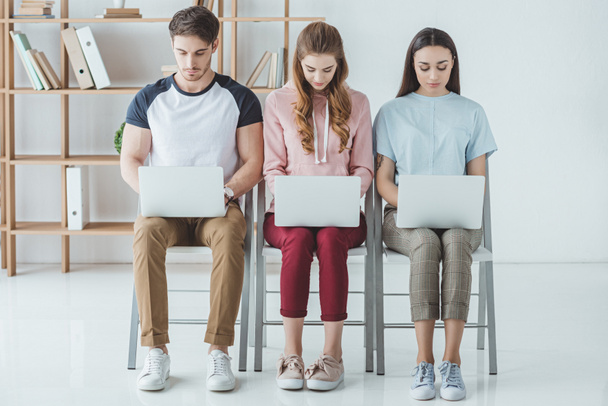 jeunes étudiants assis et étudiant avec des ordinateurs portables ensemble
 - Photo, image
