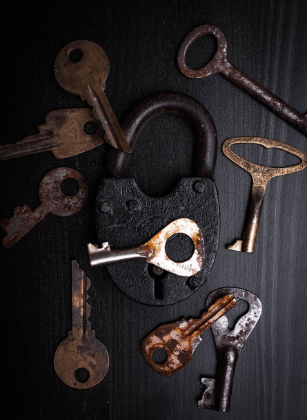 Vorhängeschloss und rostige Schlüssel auf Holzplatte  - Foto, Bild