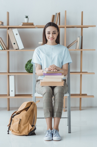 brunette student sitting with books and backpack - Fotoğraf, Görsel