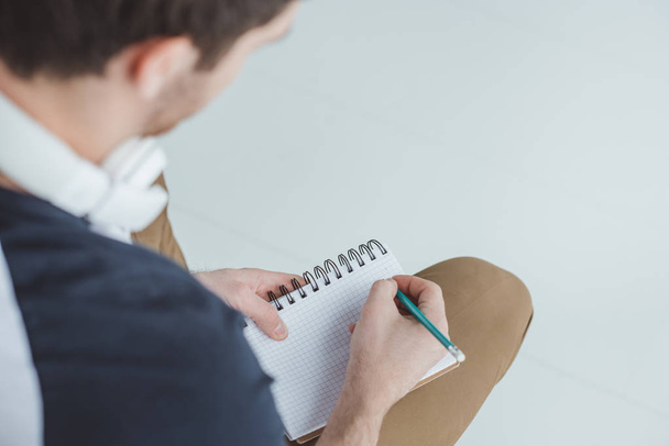 cropped view of male student with headphones writing in notebook - Foto, Bild