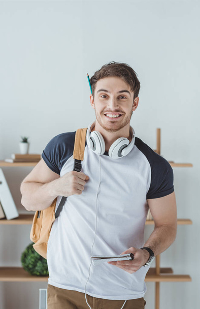 cheerful student with headphones, backpack and notebook - Fotografie, Obrázek