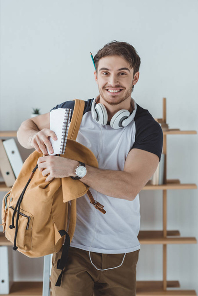 estudiante sonriente con auriculares, mochila y portátil
 - Foto, imagen