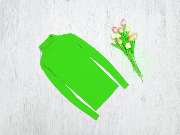 ファッションの概念。グリーンのタートルネックやピンクのチューリップ。木材の背景 - 写真・画像