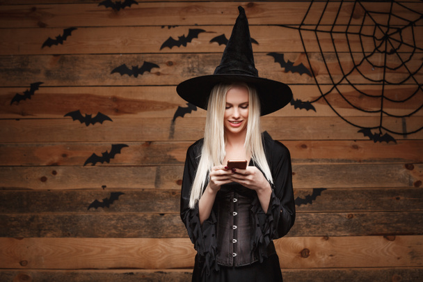 Halloween witch concept - Happy Halloween Sexy Witch holding posing over old wooden studio background. - Фото, зображення