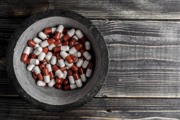 Pillen in der Schüssel auf Holzgrund. Konzept zur Tablettenabhängigkeit - Foto, Bild