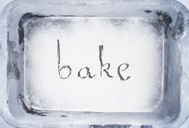 Flour.Inscription made by hand by sprinkled flour on a oven-tray - Φωτογραφία, εικόνα