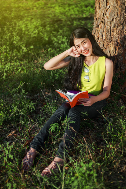 woman sitting and holding a book in the park - Foto, Imagen