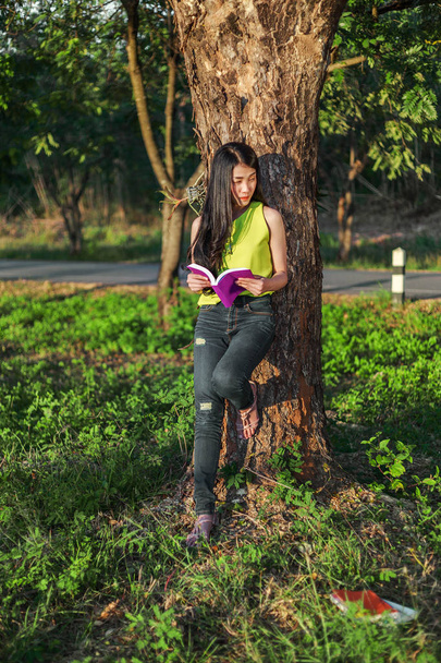 woman stading at the tree and reading a book in the park - Foto, Imagem