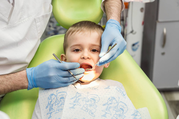 Dentist examining little boy's teeth in clinic. Dental problem. - Zdjęcie, obraz