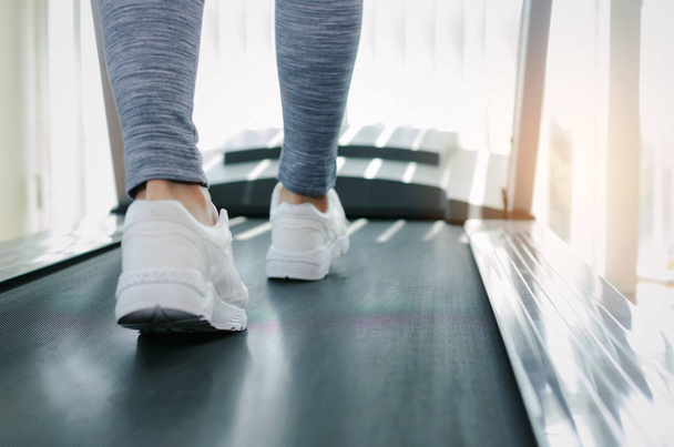 motion blur runner woman feet running on machine treadmill at fitness gym center or health club with sunlight effect, bodybuilder, healthy lifestyle, exercise fitness, workout, sport training concept - Fotografie, Obrázek