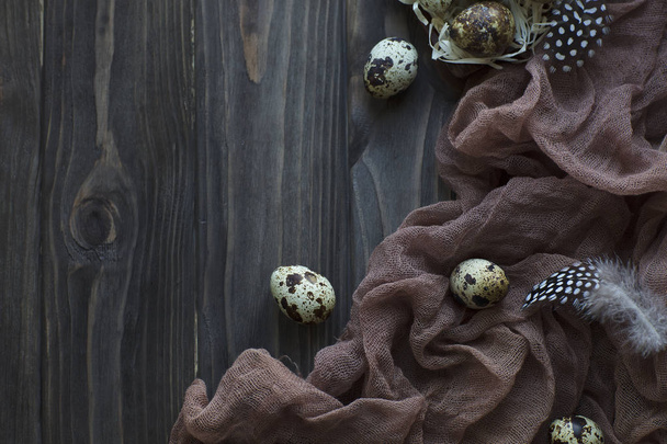 Pasen decoratie veren kwartel eieren, bruine stof grijs houten achtergrond. - Foto, afbeelding
