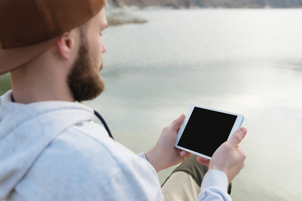 Hipster osoba trzyma w ręce cyfrowy tablet z puste pusty ekran, człowiek fotografii na komputerze, na tle przyrody pozadomowy krajobraz makieta technologii rozmycie turystyczne męskie dłonie przy użyciu gadżetu - Zdjęcie, obraz