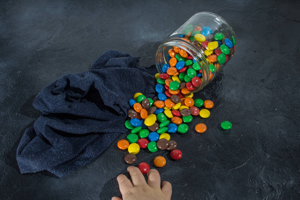вкусные красочные шоколадные конфеты в пролитой стеклянной банке
 - Фото, изображение