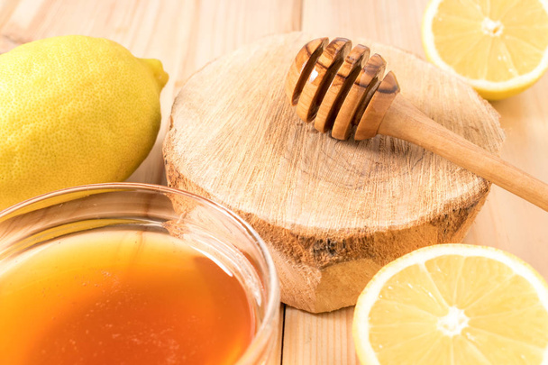 Honey with lemon on wooden background. - Foto, afbeelding