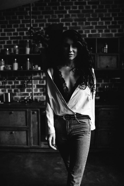Beautiful brunette in the kitchen, modern housewife, fashion, wooden brown furniture, dressed in blue jeans and a blue shirt - Φωτογραφία, εικόνα