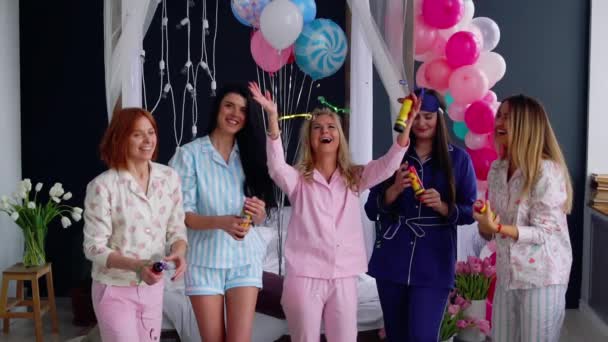 Skupina dívek v pyžamu spouštění konfety v pomalém pohybu 120 snímků za sekundu a smíchu. Přehazovat airbag lesklé cukroví na večírku - Záběry, video