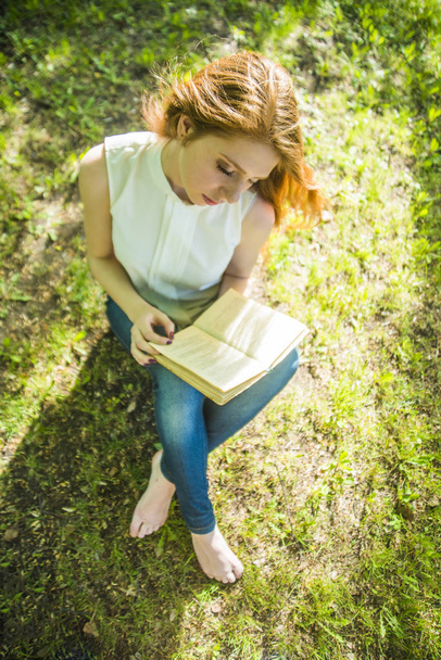vista superior. Menina lendo livro na grama verde fresca. época de primavera
. - Foto, Imagem