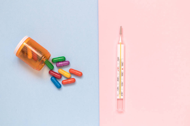 Multicolored medicines and thermometer isolated on pastel background minimalistic flat lay concept. - Foto, immagini