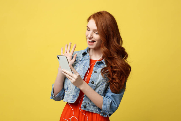 Lifestyle Concept: Young cheerful woman posing while photographing herself on smart phone camera for a chat with her friends, attractive smiling hipster girl making self portrait on cell telephone. - Photo, Image