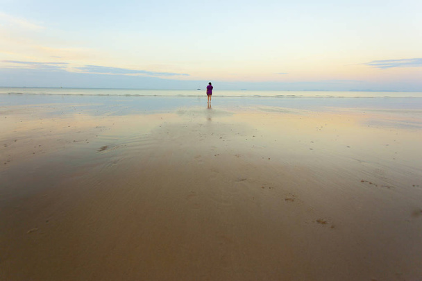 Lonley γυναίκα που περπατά στην παραλία πέρα από την δύση του ηλίου - Φωτογραφία, εικόνα
