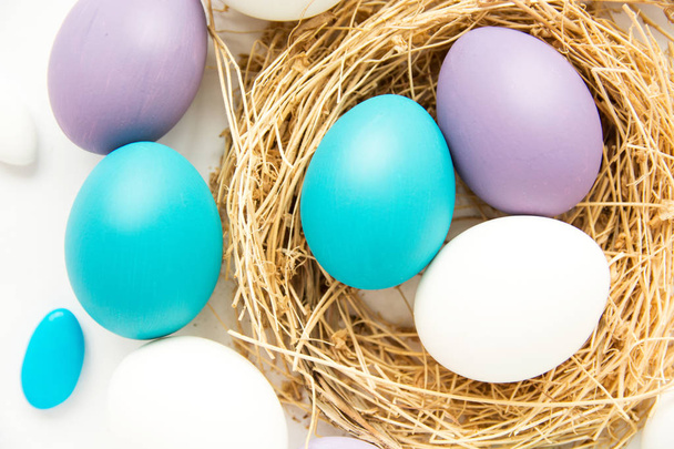 colored blue and purple Easter eggs in nest on wooden background, selective focus image. Happy Easter card  - Foto, Imagem
