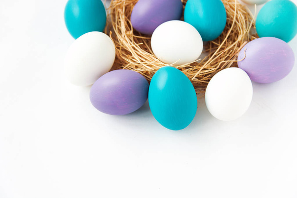 colored blue and purple Easter eggs in nest on wooden background, selective focus image. Happy Easter card  - Foto, Imagen