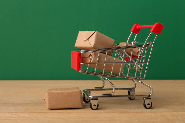 Miniatur-Einkaufswagen und Pakete auf braunem Hintergrund, - Foto, Bild