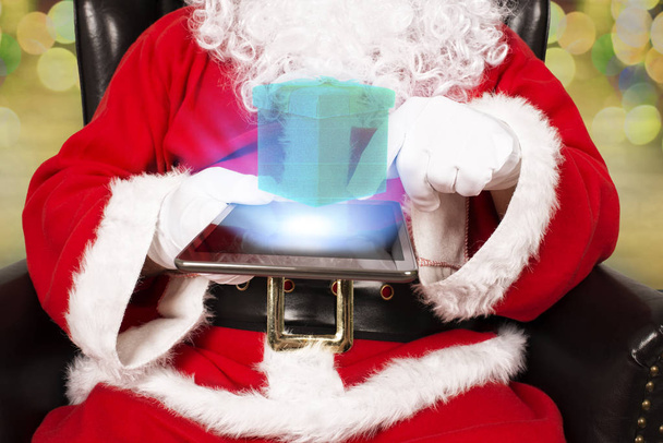 Le Père Noël tient et touche une tablette numérique. Gros plan sur les mains
. - Photo, image
