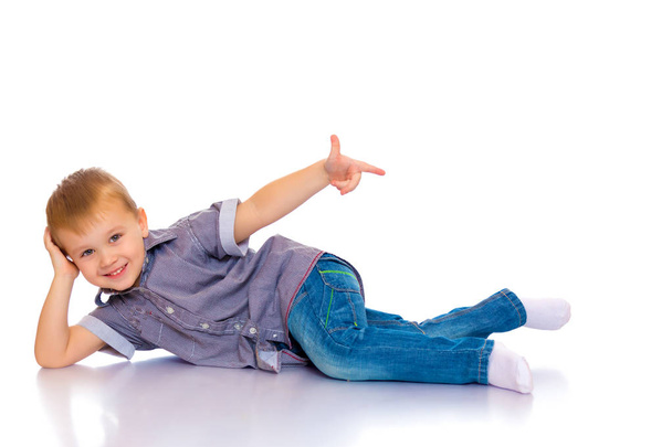 Щасливий маленький хлопчик лежить на підлозі в студії
. - Фото, зображення