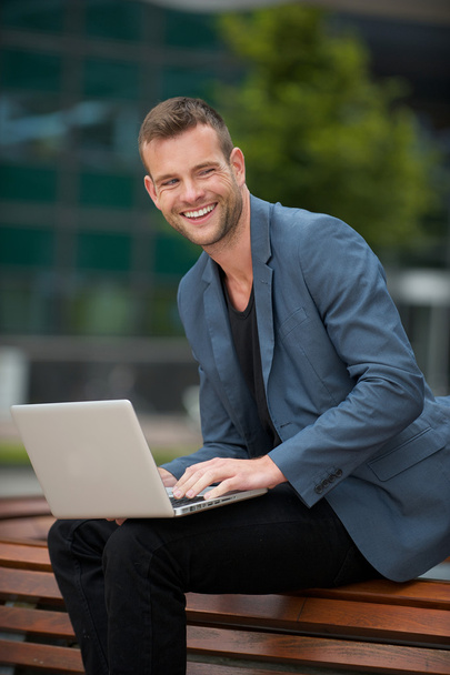 zakenman lachend met laptop outdoors - Foto, afbeelding