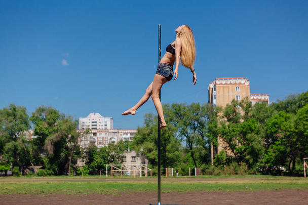 Fit attractive girl dancing near portable pole at summer day on the field - Фото, изображение