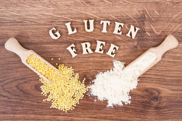 Inscription gluten free with millet groats and flour on wooden scoop, healthy food - Фото, изображение