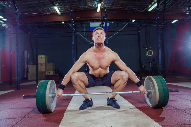 Muscular fitness man preparing to deadlift a barbell over his head in modern fitness center.Functional training.Snatch exercise. - Foto, immagini
